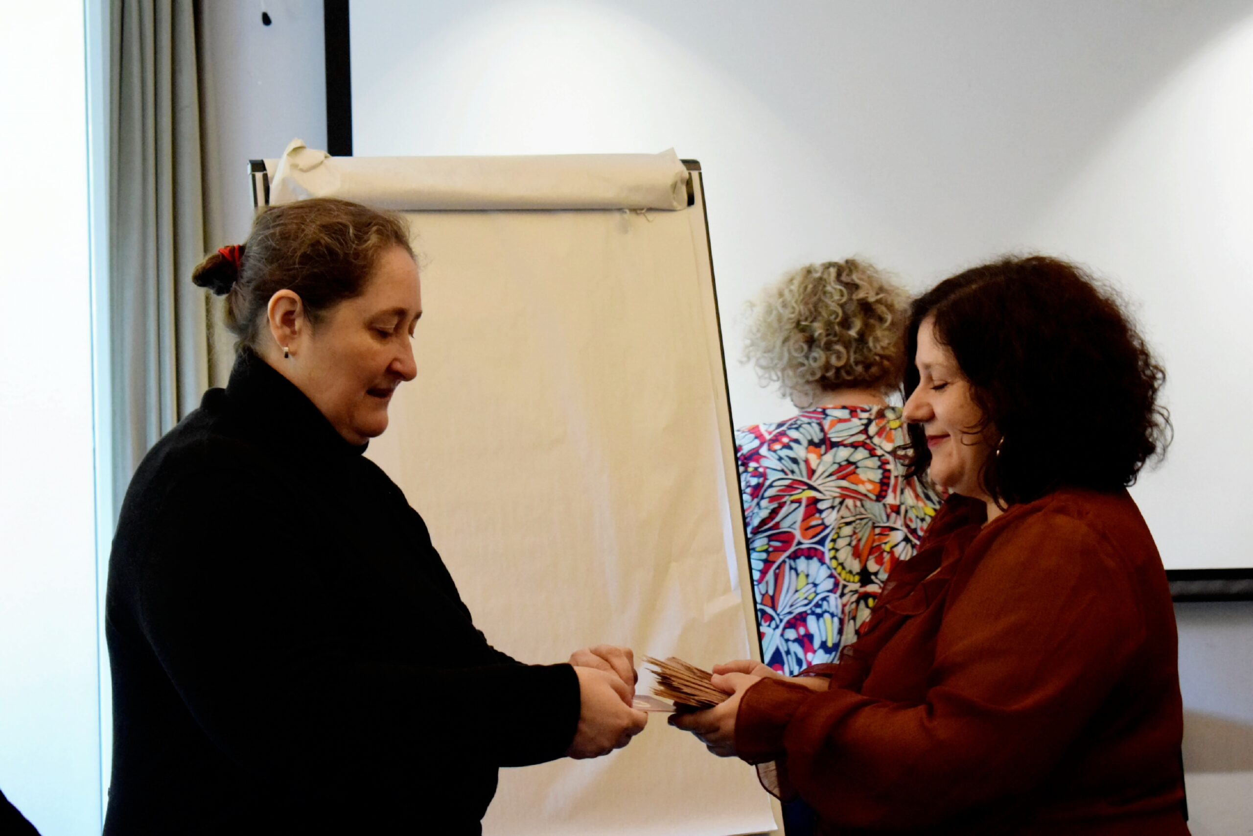 Linda Dragoni remet une carte d’intention à une participante lors de l’accueil d’un séminaire Déploie tes ailes